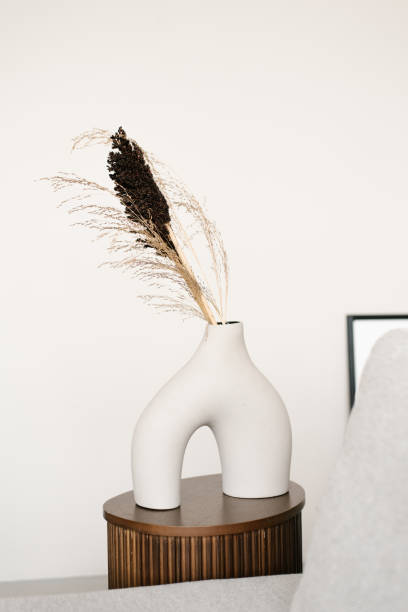 istock Stylish modern white ceramic vase interestingly shaped white ceramic vase with dried flowers in the decker of a Scandinavian living room or bedroom room 2149633050