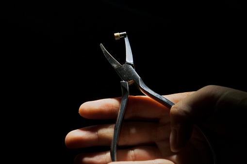 Orthodontist's tool, pliers close up on female hand
