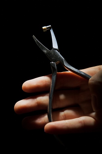 Orthodontist's tool, pliers close up on female hand