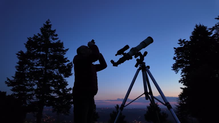 Amateur astronomer looking at the evening skies, observing planets, stars, Moon and other celestial objects with a telescope and binoculars.