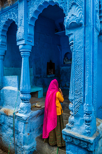 Young Indian woman walking inside a Blue City. Jodhpur is known as the Blue City due to the vivid blue-painted houses around the Mehrangarh Fort.