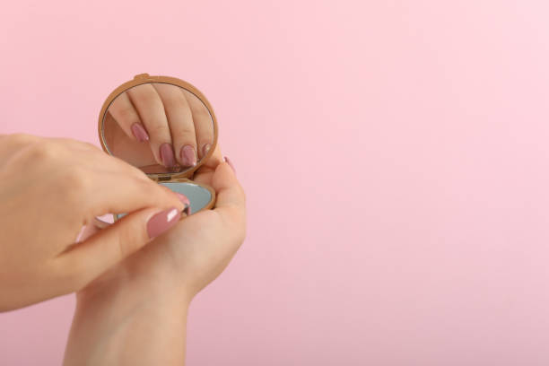 istock Beautiful female hands with mirror on pink background 2149634734