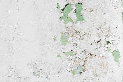 An image showcasing the texture of a weathered wall with layers of peeling paint that reveal the passage of time and neglect
