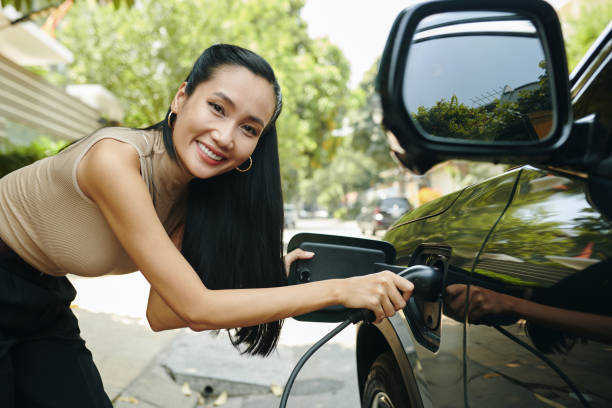 istock Woman Inserting Plug in Electric Car 2149637664