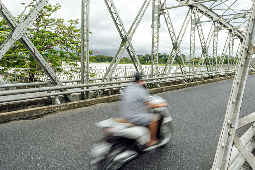 motion blurred motor scooter on iron Truong Tien bridge in Hue, Vietnam