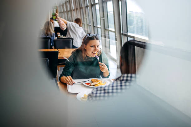 Two young colleagues together on a lunch break enjoying meal and working same time