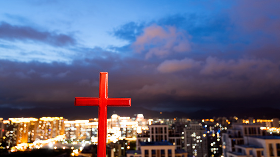 Religious cross on city background.