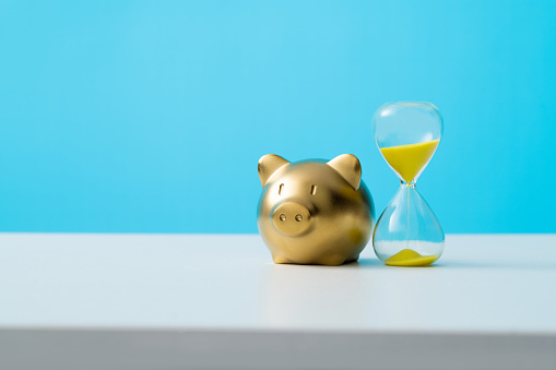 Piggy bank with hourglass on the table.