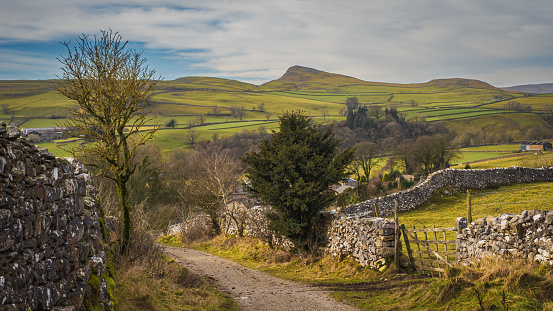 Goat Scar Lane, is a Dales green lane flanked by drystone walls. The leading lines of the walls draw the eye to the dramatic hills of Pot Scar and Smearsett Scar, limestone waves frozen in time.