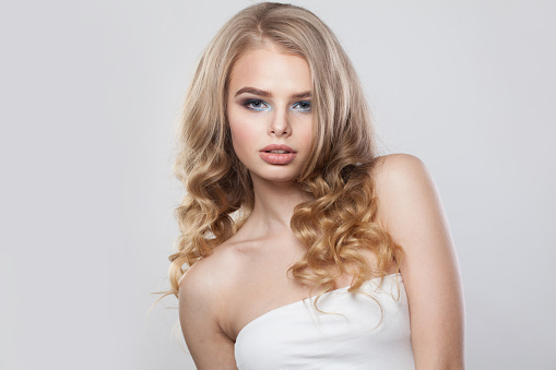 Beautiful young fashion woman with healthy blonde hair and make-up on white background