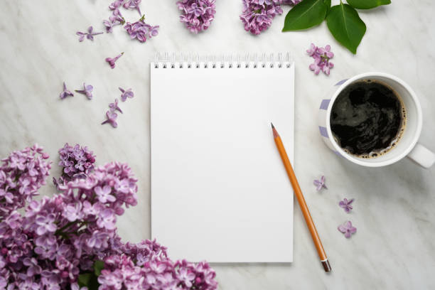 istock Spring flatlay. Notebook with pensil, lilac flowers, and cup of coffee on light background. 2149644897
