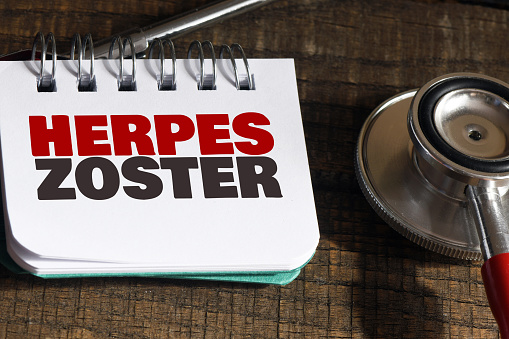 HERPES ZOSTER words in an office notebook next to a stethoscope.