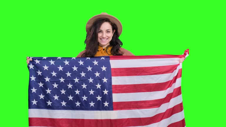 Happy young woman posing and holding USA flag on the chroma key