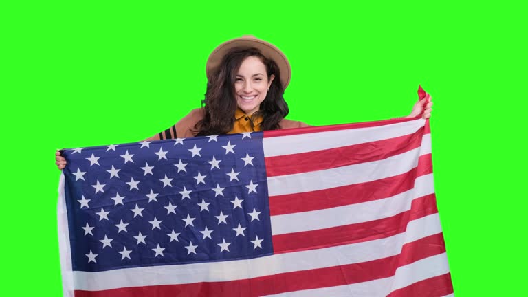 Happy stylish woman sending air kiss and holding USA flag on the chroma key