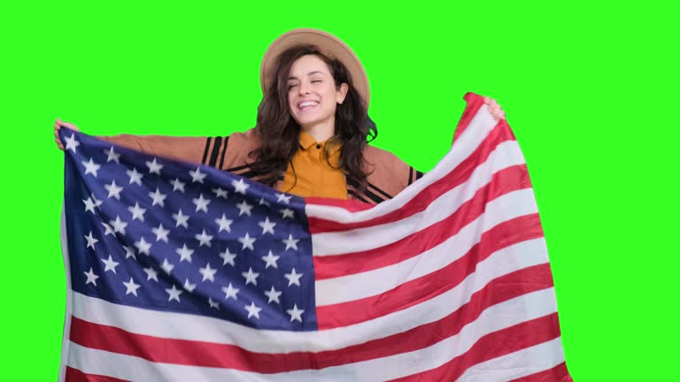 Happy woman in stylish hat celebrating with USA flag on the chroma key