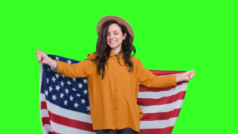 Happy woman in hat holding USA flag while celebrating on the chroma key