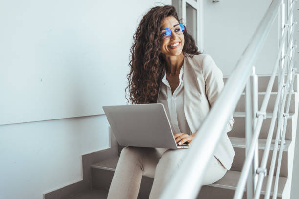 istock Side view of businesswoman using laptop while sitting on steps. 2149649581
