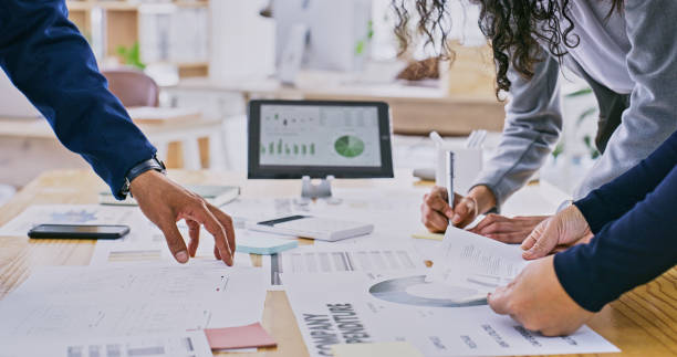 istock Business hands, teamwork and documents for data analysis, budget report and writing or expenses on tablet screen. Professional group of people in meeting with statistics, graphs or charts for finance 2149651518