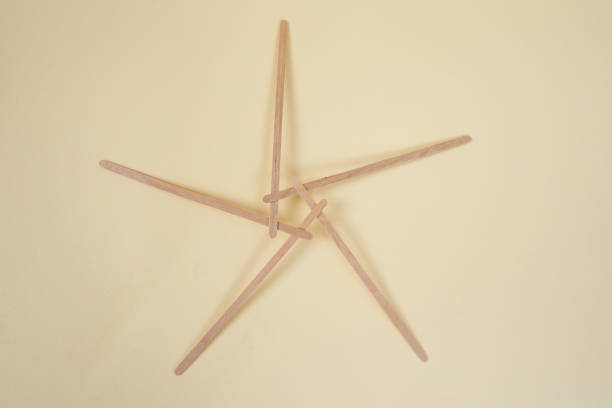 Bamboo wooden sticks demonstrating a pentagram reciprocal frame structure, on beige