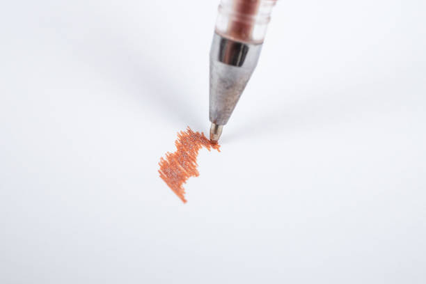 Brown glitter ink ball pen scribbling on white paper, soft focus