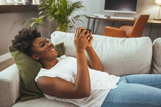 istock Shot of a young woman using a cellphone while relaxing on a sofa at home 2149655115