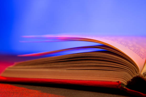 Close-up of Book Pages. Shows a close-up of the edges of stacked books or documents. The corner of the top page is slightly curved, revealing the layers beneath. The white background highlights the texture and detail of the paper edges.