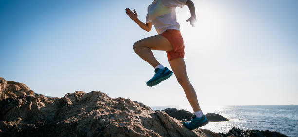 istock Woman runner running on sunrise seaside rocks 2149658247