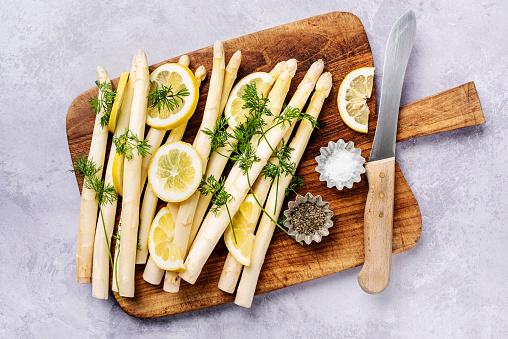Preparing a dish of fresh seasonal white asparagus with lemon and dill.