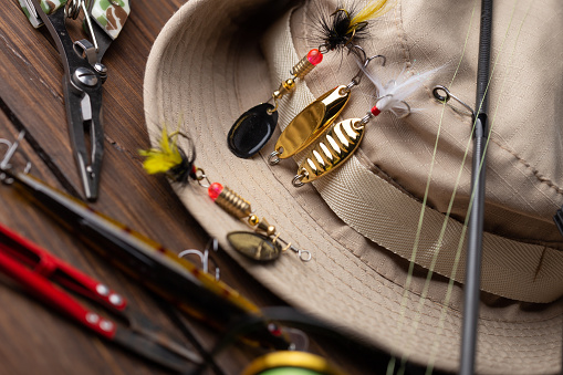 Fishing tackle - fishing spinning rod, hooks and lures on vintage wooden background. Active hobby recreation concept. Top view, flat lay.