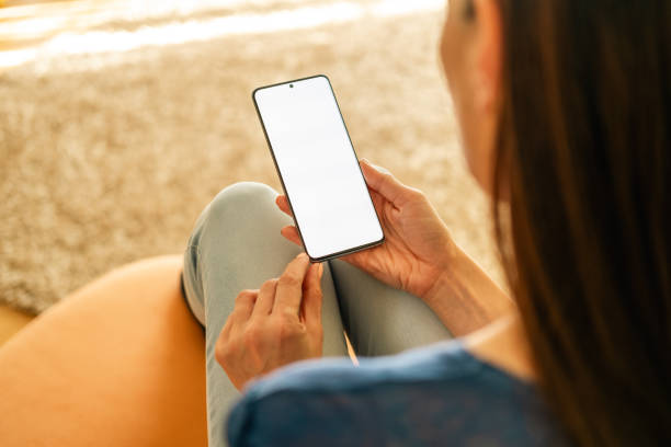 istock A woman looking at telephone screen, sitting on the sofa. 2149658680