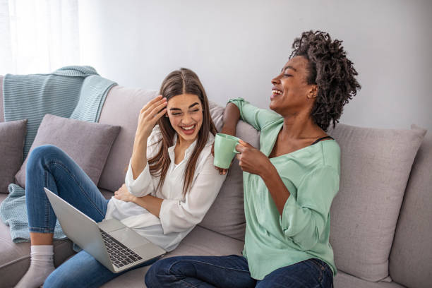 Female friends having fun at home, using laptop computer