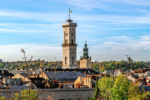 Lviv, Ukraine - November 2, 2023: Top view of the city panorama and the chapel of the Lviv Town Hall on an autumn morning. Close-up of city roofs against the backdrop of bare tree branches