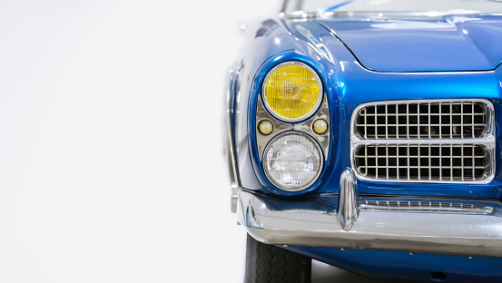 Front view of a blue vintage car. Classic car. Headlights. Copy space. White background.