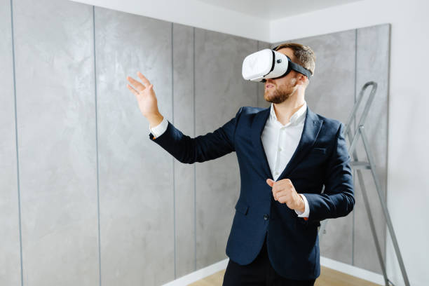 istock Young man wearing VR glasses, scrolling with hands in air using futuristic innovative technology choosing home design. Repair and renovation concept. Virtual reality 2149659401
