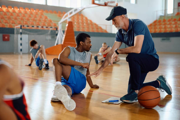 istock Basketball coach assisting his player with stretching exercise on the court. 2149659955
