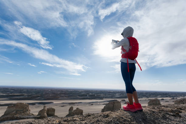 Successful woman hiker use smartphone on the sunset desert