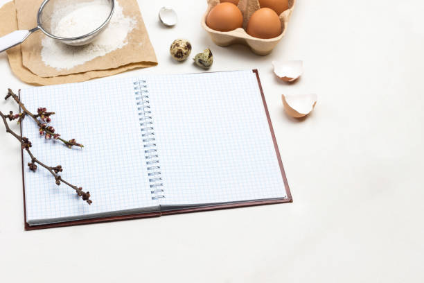 istock Notebook on springs. Two wooden spoons. Chicken eggs and chicken shells. Flour and sieve on paper 2149662265