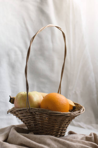 Still life composition of fruit in a wicker basket in a soft, cozy space. Healthy nutrition concept.