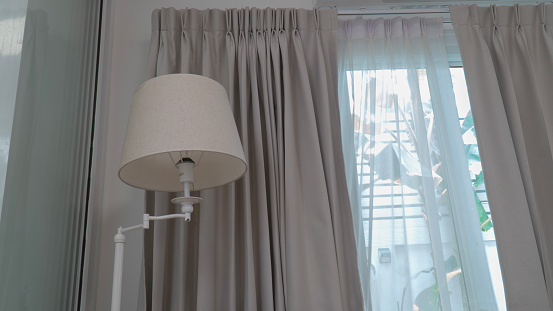 A floor lamp and a sheer curtain in front of a window
