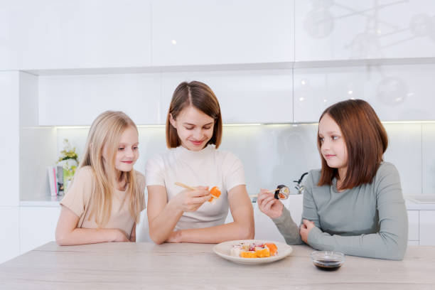 istock woman is feeding her two daughters sushi 2149665729