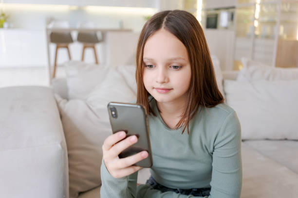 istock A girl is sitting on couch and looking at her cell phone 2149665829