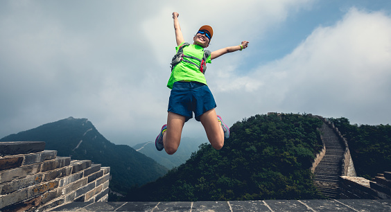Successful woman hiker jumping on great wall
