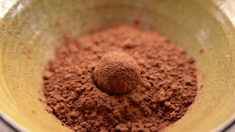 A bowl of chocolate powder with a small chocolate ball in the middle