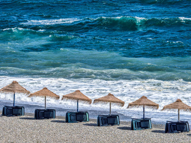 Beach umbrellas lined up on sandy beach in Almunecar, Spain.