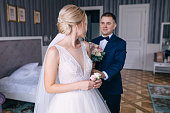 the groom enters the bride's room with a bouquet. Girl holding b