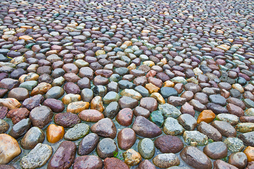 Detail of a coloful rounded pebble floor, permeable to water, with polished stone in a italian square.