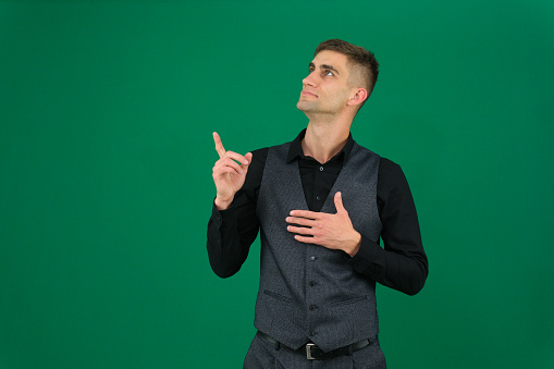 emotions of a handsome man guy on a green background chromakey close-up dark hair young man. young man doing a winner gesture