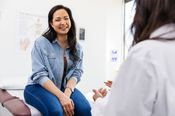 istock Mid adult female patient smiles while talking with her doctor 2149681136