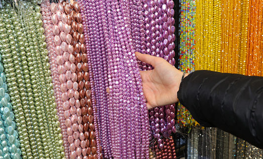 choosing a pearl necklace among many hanging in the fashion accessories store in the shopping center