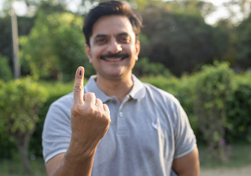 Portrait of man shows his finger marked with ink casting vote in Election